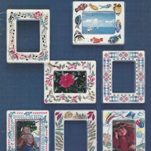 May include: A collection of magnetic frames with various designs. The frames are rectangular with decorative borders featuring musical notes, flowers, fish, and geometric patterns. Some frames contain photos, and the text "MAGNETIC FRAMES" and "I've Been Framed" are visible.