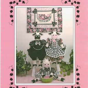 May include: A pink flyer with the text "Precious Collections" and "Down the Lane." It features three cow dolls, each with unique outfits, and a matching quilt. The dolls are approximately 18 inches tall. The flyer includes text about the dolls.