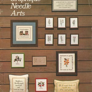 May include: A collection of framed needlepoint art pieces and decorative pillows. The artwork includes floral designs, inspirational quotes, and a house scene. The text "Graphique Needle Arts" is at the top.