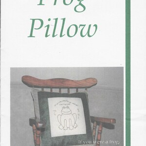 May include: A wooden rocking chair with a pillow featuring a frog design. The pillow has the words "Frog Pillow" at the top and the text "If you were a frog, then you could eat what bugs you" at the bottom. The pillow is green and white.