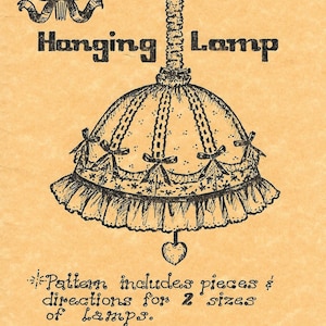 May include: Vintage illustration of a "Cotillion Hanging Lamp" pattern. The design features a detailed drawing of a lampshade with a ruffled edge, bows, and a heart-shaped pendant. The text includes "The Calico Factory".