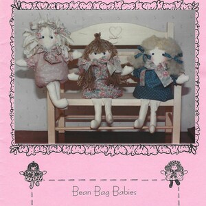 May include: A sewing pattern sheet titled SEW SPECIAL featuring three fabric dolls sitting on a small wooden bench. The dolls have yarn hair and patterned dresses. The text includes Bean Bag Babies and 7 inches tall. The background is pink.