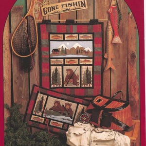 May include: A rustic-themed display featuring fishing-related decor. Includes a fishing net, a wooden sign reading "GONE FISHIN'," and a decorative wall hanging with a bear and fish motif. A fishing vest and tackle box are also visible.