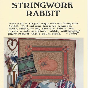 Könnte beinhalten: Eine Bastelanleitung mit dem Titel Stringwork Rabbit von Judy Roth, bestehend aus einem beigen Quilt mit rosa Hasenapplikation, einem grünen Kissen mit Hasensilhouetten und zwei ausgestopften Stoffhasen mit blau-roten Mustern, datiert 1988.