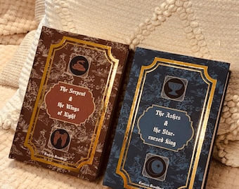 May include: Two hardcover books with gold trim and decorative covers. One book is brown with the title "The Serpent & the Wings of Night." The other is blue with the title "The Ashes & the Star-cursed King."