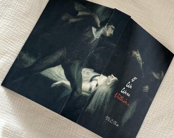 May include: A book with a dark cover featuring a dramatic painting of figures in a dimly lit scene. The title "If We Were Villains" is in red script, with the author's name below. The book is open, revealing the inside pages.
