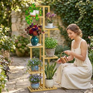 May include: A tall, light-colored wooden plant stand with multiple shelves holding various potted plants, including a teal vase with a colorful floral arrangement, a snake plant, and a small watering can being used to water the greenery.
