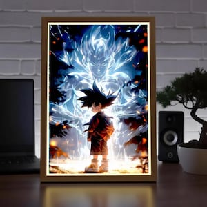 Può includere: Stampa artistica di anime incorniciata. L'opera raffigura un ragazzo in abito rosso e nero, in piedi davanti a una figura blu brillante. Lo sfondo mostra una foresta e una luce intensa. La cornice è in legno.