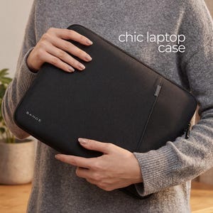 May include: A black laptop case with the text "chic laptop case" in white. The case has a zip closure and a small silver accent. The brand name "BANGE" is visible on the lower left corner.