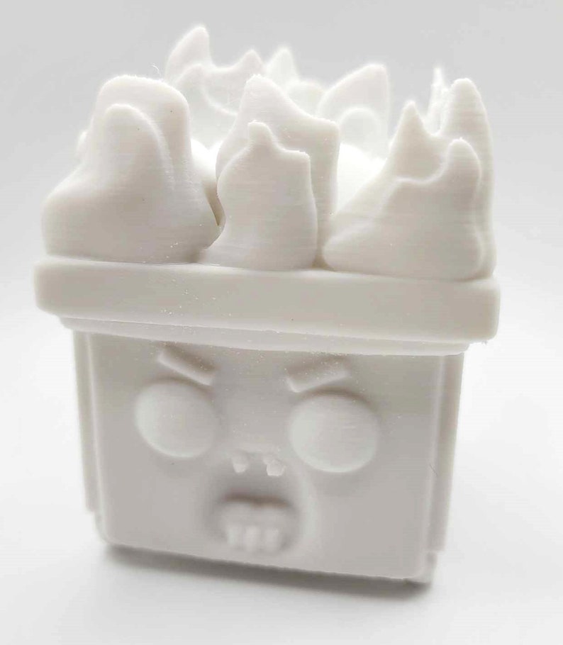 Peut inclure: Jouet en plastique blanc avec un visage de dessin anim&eacute; et une couronne de flammes. Le jouet a une expression grincheuse avec les sourcils fronc&eacute;s et la bouche ouverte.