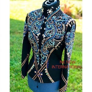Könnte beinhalten: Schwarze Reitjacke mit aufwendiger blauer und türkisfarbener Stickerei und Verzierungen. Die Jacke hat einen hohen Kragen und lange Ärmel mit einer taillierten Silhouette. Das Design umfasst Scrollmuster und funkelnde Akzente.