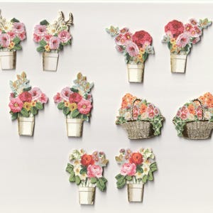 May include: A collection of floral embellishments in various arrangements. The designs include bouquets in white pots, some with gold antlers, and baskets filled with colorful flowers. The flowers feature pink, red, and yellow blooms.