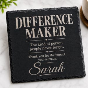 May include: A square black slate coaster with rough, chiseled edges. The surface is engraved with the text: DIFFERENCE MAKER, The kind of person people never forget. Thank you for the impact you've made. Sarah. The lettering is in a light gray tone.