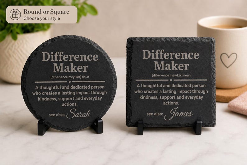 以下が含まれることがあります： 「Difference Maker」の文字と定義が書かれた、丸と四角の黒いスレートコースター2つ。丸いコースターには「see also: Sarah」、四角いコースターには「see also: James」と書かれています。どちらも黒いスタンドに置かれています。