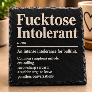 Könnte beinhalten: Eine quadratische schwarze Schieferplatte mit rauen, strukturierten Kanten. Der weiße Text lautet: Fucktose Intolerant, noun, An intense intolerance for bullshit. Common symptoms include: eye-rolling, razor-sharp sarcasm, a sudden urge to leave pointless conversations.