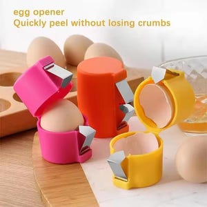 May include: Egg openers in pink, orange, and yellow, with a stainless steel blade. The text "egg opener Quickly peel without losing crumbs" is visible. The openers are designed to peel eggs.