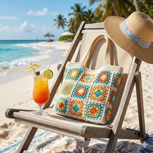 May include: A colourful crocheted tote bag with a square pattern in turquoise, orange, and yellow sits on a beach chair next to a straw hat. A tropical drink with a lime and umbrella garnish is also on the chair.