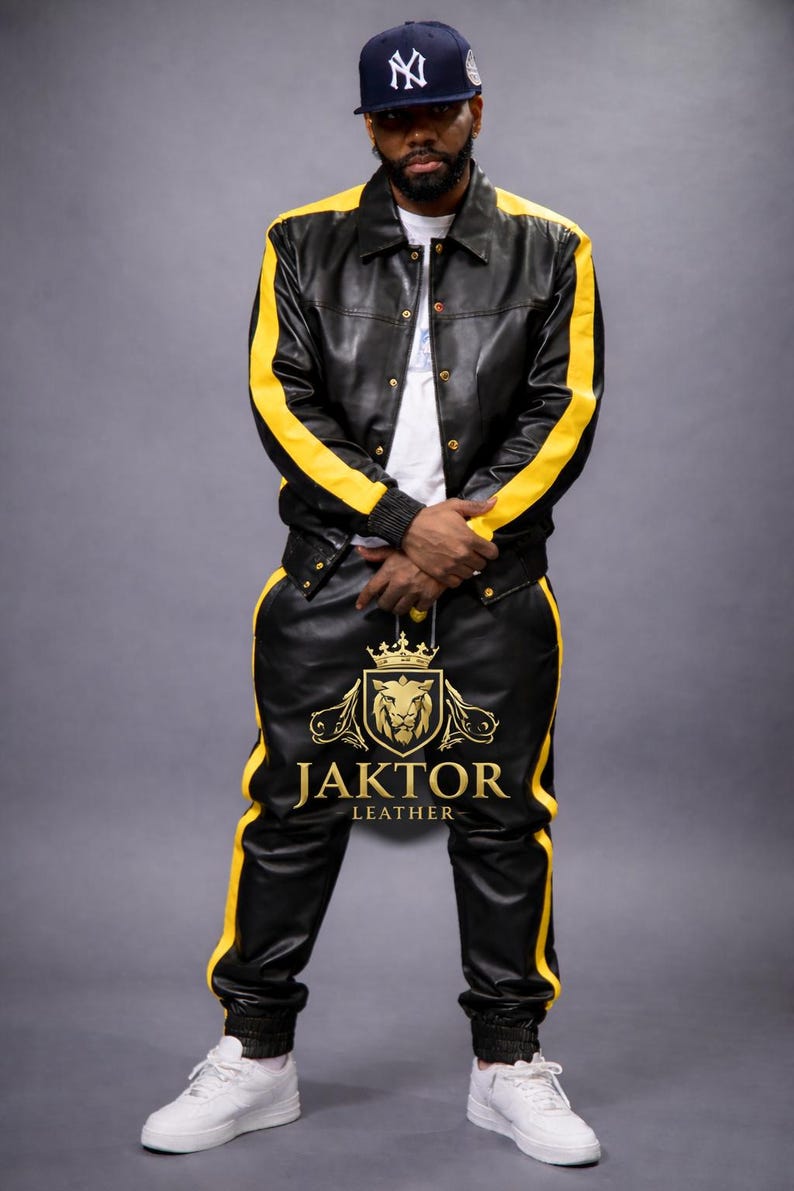 K&ouml;nnte beinhalten: Schwarzes Lederjacken- und Hosen-Set mit gelben Streifen. Die Jacke hat eine Knopfleiste und die Hose ein Logo am Bein. Das Set ist von Jaktor Leather.