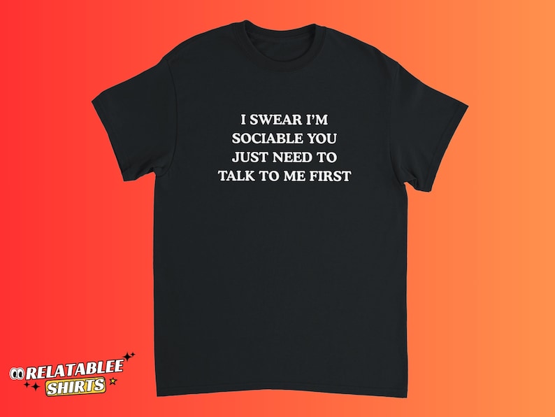 May include: Black t-shirt with the text "I SWEAR I'M SOCIABLE YOU JUST NEED TO TALK TO ME FIRST" in white. The shirt has short sleeves and a crew neck. The brand logo "RELATABLEE SHIRTS" is in the bottom left corner.