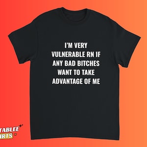 Puede incluir: Camiseta negra con texto blanco: "I'M VERY VULNERABLE RN IF ANY BAD BITCHES WANT TO TAKE ADVANTAGE OF ME." La camiseta tiene mangas cortas y cuello redondo. El fondo es un degradado de naranja y rojo.