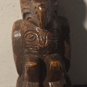 May include: A carved wooden owl figurine with a dark brown finish. The owl has detailed features, including large eyes, a prominent beak, and carved feathers. The figurine is standing on a small base.