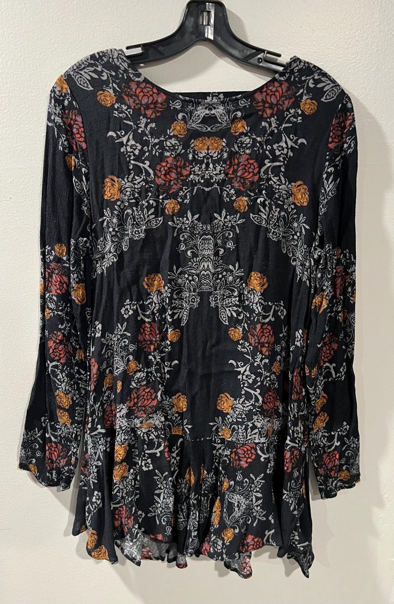 May include: A black long-sleeved dress with a floral print in shades of white, orange, and red. The dress has a round neckline and a flowing skirt.