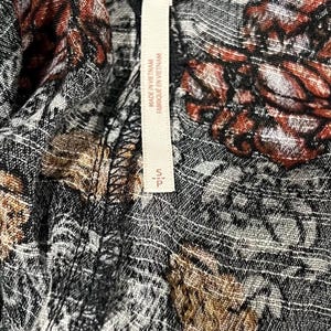 May include: A black and white floral print fabric with a Free People tag attached. The tag is white with black text that reads "Free People" and "Made in Vietnam / Fabrique en Vietnam".