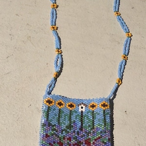 May include: A beaded necklace with a blue and yellow chain and a beaded pouch with a floral design and red fringe.