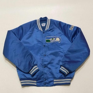 May include: A bright blue satin varsity jacket featuring a snap-button front closure, striped ribbed collar, cuffs, and hem. The chest displays an embroidered bird logo patch, while the word Team is stitched in white on the upper left sleeve.