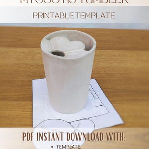 May include: A light-colored, cylindrical ceramic tumbler with a flower-shaped opening at the top. The image includes text reading MYOSOTIS TUMBLER PRINTABLE TEMPLATE and PDF INSTANT DOWNLOAD WITH: TEMPLATE. STEP BY STEP INSTRUCTIONS ESPAÑOL + ENGLISH.