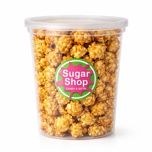 May include: A clear plastic container filled with caramel popcorn. The container has a clear lid and a circular sticker with the text "Sugar Shop CANDY & GIFTS" in pink and green. The popcorn is golden brown.