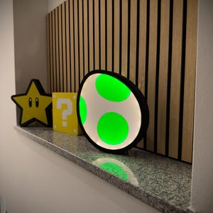 May include: A decorative shelf displays a yellow star, a yellow question mark box, and a large egg-shaped light with green accents. The egg light has a black border and three green circles. The background features vertical wooden slats.