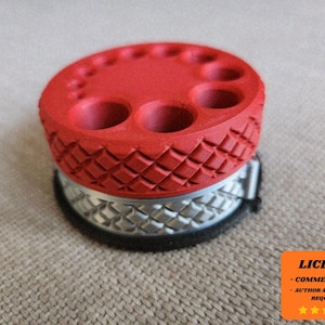 May include: A red and silver 3D-printed tool holder. The top is red with multiple holes of varying sizes. The base is silver with a diamond pattern. The holder is designed to organise tools.