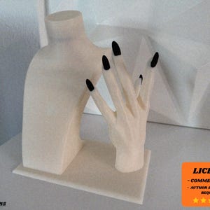 Puede incluir: Expositor de joyería color crema con un busto y una mano con uñas negras. El busto tiene forma redondeada en cuello y hombros. La mano está posada con los dedos extendidos. El expositor se encuentra sobre una base rectangular.