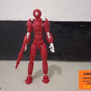 May include: A red articulated action figure of a humanoid robot, holding a gun-like weapon. The figure has white hands and feet. The image includes an orange square with the word "LICENSE" and other text.