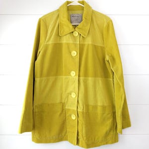 Peut inclure: Une veste en velours côtelé chartreuse présentant un design color-block avec des panneaux horizontaux de différentes nuances de jaune-vert. La veste comprend un col pointu, des manches longues, cinq boutons assortis sur le devant et deux grandes poches plaquées.