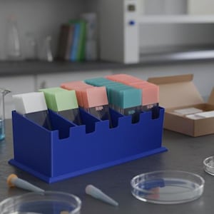 May include: A laboratory scene featuring a microscope, petri dishes, and a blue container holding various colored slides. The microscope is black and white. Other lab equipment is also visible on the gray countertop.