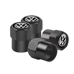May include: Set of four black tire valve stem caps. Each cap features a white and black Volkswagen logo. The caps are made of a shiny, metallic material and are arranged on a white background.