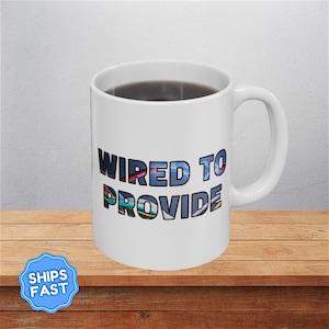 May include: A white ceramic mug with a black handle and the text "But First, Coffee" in a bold, black font. The mug is sitting on a wooden surface. The mug is approximately 4 inches tall.