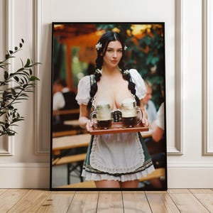 May include: A framed print featuring a woman in traditional German attire, holding a tray with two mugs of beer. The woman has dark hair and is wearing a white blouse, a green bodice, and a white apron. The background shows a blurred outdoor setting.