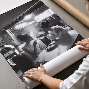 Vintage diner women pie poster being unrolled on concrete surface showing premium photo paper quality print with hands in white shirt revealing black white photography
