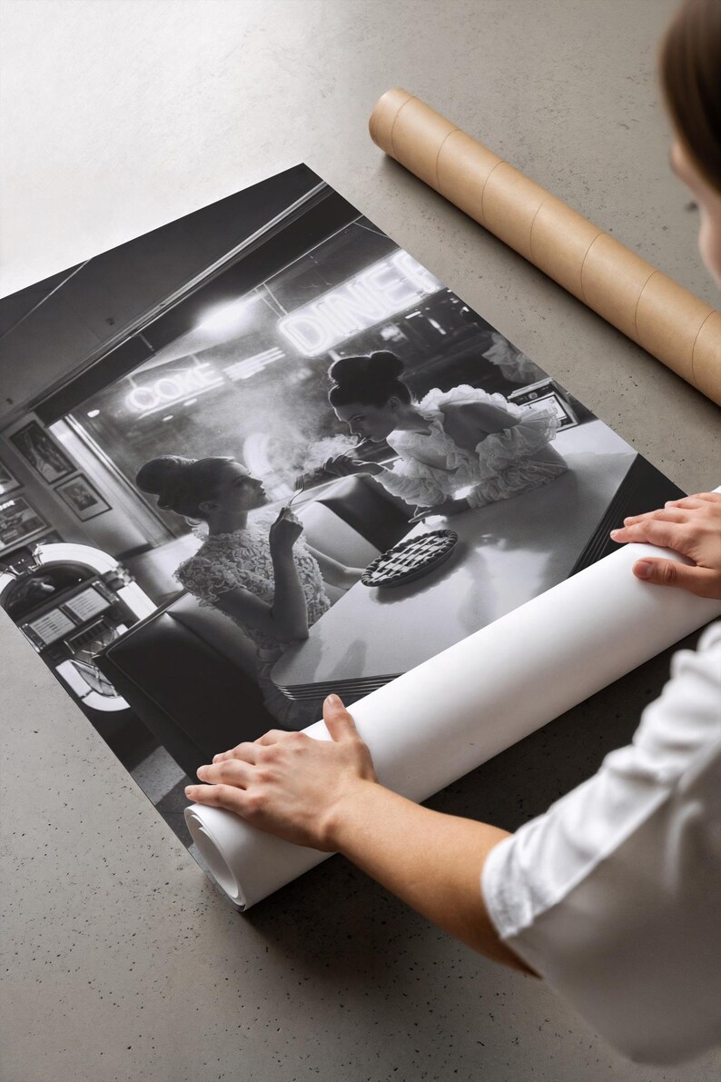 Vintage diner women pie poster being unrolled on concrete surface showing premium photo paper quality print with hands in white shirt revealing black white photography