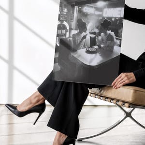 Classic diner neon poster held by woman in black business attire and heels against white wall showing vintage 1950s women at jukebox photography print