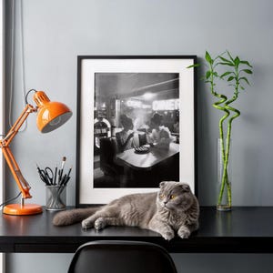 Black white diner ladies with pie poster on home office desk with orange vintage lamp gray cat lucky bamboo plant and modern workspace decor