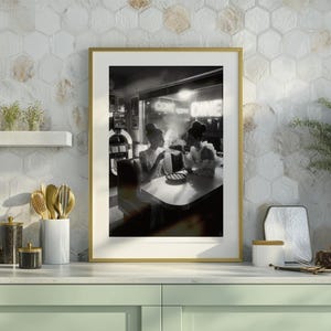 50s diner women jukebox poster in gold brass frame displayed on modern kitchen counter with hexagon tile backsplash sage green cabinets and gold kitchen accessories