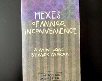 May include: A mini zine titled "Hexes of Minor Inconvenience" by Mick Moran. The cover features a purple and gray floral design at the top, with the title in large white letters. The Impostor Monster zine logo is at the bottom.