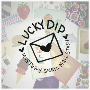 May include: A close-up of a collection of colorful cards and envelopes with the text "Lucky Dip Mystery Snail Mail Stash" written in black marker. The cards feature various illustrations, including a snail, a fox, a unicorn, and a hot air balloon.