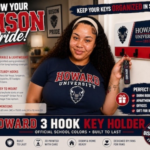 May include: A rectangular Howard University 3-hook key holder featuring the school logo, name, and 1867 founding year in navy, red, and white. The wall-mounted organizer includes three black hooks and measures 169.65 mm wide by 79.65 mm high by 10 mm deep.
