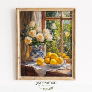 May include: An oil painting in a wooden frame depicting a blue and white ceramic pitcher filled with white roses next to a bowl of bright yellow lemons on a white cloth, set before a window with a view of green foliage and sunlight.
