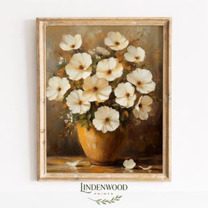 May include: A framed oil painting print featuring a bouquet of white flowers with dark centers arranged in a golden-yellow vase. The artwork displays a warm, earthy color palette with visible brushstrokes and scattered petals on the surface.